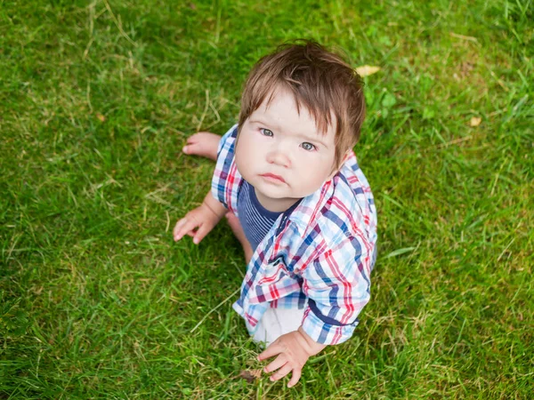 A criança está a olhar para cima. no fundo de grama verde — Fotografia de Stock