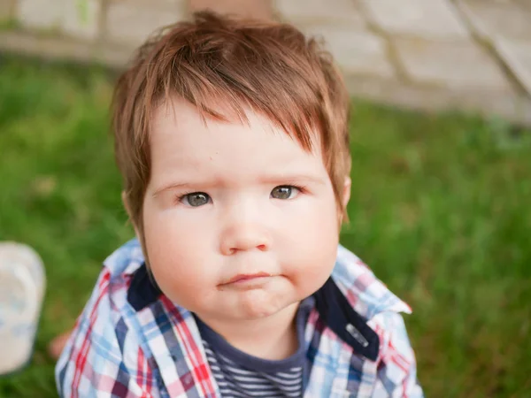 Cara a um bebê de um ano de idade fechar. garoto bonito com bochechas grandes e cabelo castanho — Fotografia de Stock