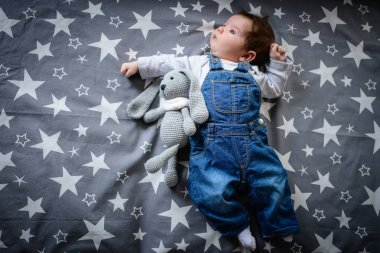 Yatakta pelüş oyuncağı olan bir bebek. Tavşan şeklinde bir oyuncak. Uyumak için favori bebek oyuncağı.