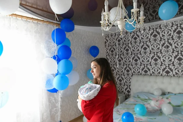 Golyók a szobában egy fiatal anyának. meglepetés otthon. Egy új családtag születésének ünneplése. Anya egy gyerekkel a hálószobában. Boldog szerető család.. — Stock Fotó