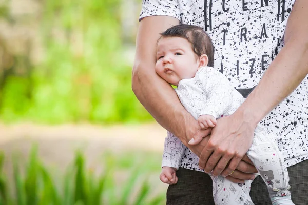 Baby girl in the loving hands of father. Close-up portrait of new born baby sleeping in male arms. Young happy father holding baby smiling. Indoor shot, concept image. Motivational text The best thing