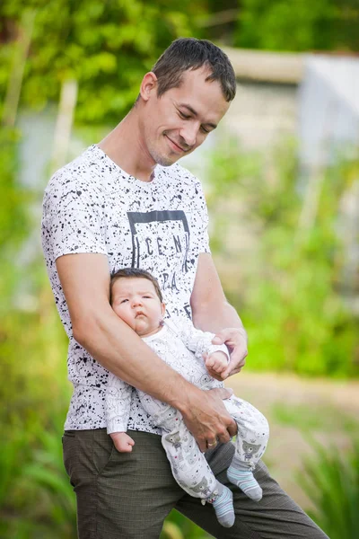 Baby girl in the loving hands of father. Close-up portrait of new born baby sleeping in male arms. Young happy father holding baby smiling. Indoor shot, concept image. Motivational text The best thing