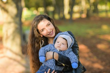 Ciddi çocuk. Annesinin kollarında pozitif bir anne. Ciddi bir bebeğin portresi.