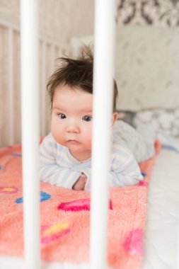 Beşikteki bir bebeğin portresi. Güzel bir bebeğin yüksek açılı portresi, ağzında bir parmak, yatakta yatıyor, gözleri sonuna kadar açık, uykudan uyanmış.