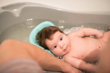 Baba kızını yıkıyor. Bir bebeğin portresi evde küvet kullanarak babası tarafından yıkılıyor.