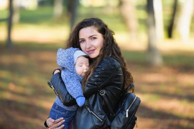 Yürüyüşte uyuyan bebek. Uyuyan küçük kız, sonbahar parkında annesinin omzunda bir oğlan.