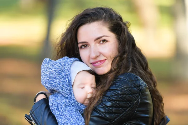 Bebek annesinin kollarında uykuya daldı. Annenin sıcak kucaklaması bebeği sakinleştirdi. Uyumak için sıcak hava. Annenin kollarında güvende.