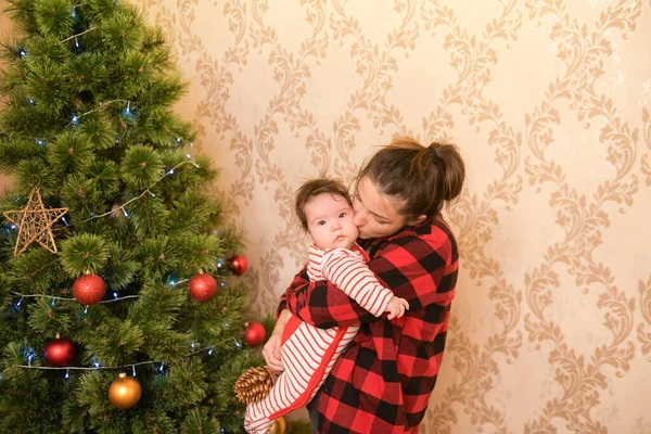 Noel ağacının yanında çocuklu bir anne. Ağacı topla ve tatil için hazırlan. Sevimli, açık renk saçlı, güzel annesi kalın kazaklar giyen ve gülümseyen bir kızın yarım boy portresi. — Stok fotoğraf
