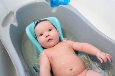 Banyoda yıkanan bebek. Baba oğlunu beyaz bir küvette yıkıyor..