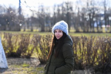 Sıcak örülmüş şapkalı bir kız. Gri örgü şapkalı genç bir mankenin portresi. Sokakta yürürken