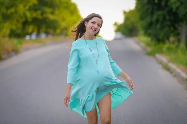 Feliz joven embarazada. sobre un fondo verde. con un vestido cómodo. Retrato de una mujer embarazada feliz y alegre — Foto de Stock
