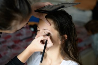 Makyöz göz boyar. Makyaj sanatçısı tarafından makyaj yapılmış bir kadının yakın plan portresi.