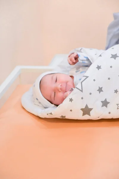 Baby wrapped in a blanket. Sleeping Cute Newborn Infant Wrapped in Baby Blanket in Acrylic Hospital Bassinet just after Birth