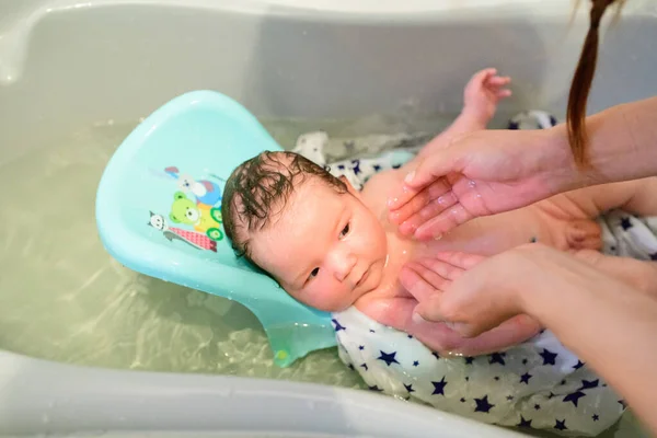 Купание ребенка. купает сына в маленькой пластиковой ванне — стоковое фото