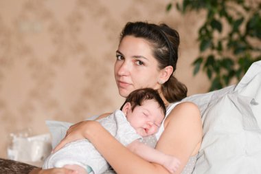 Bebek kollarında annesiyle uyuyor. Anne ve yeni doğmuş bebek. Anne kucağına alır ve kucağına alır, yeni doğan bebek annesinin göğsünde uyur, hafif yumuşak bir ton, annelik kavramı ve...