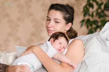 Anne elleri. Anne, yeni doğan oğlunun başını tutuyor. Ellerindeki bebek anneye bakıyor. Sevgi dolu bir anne eli kucağında tatlı, uyuyan bir bebek.