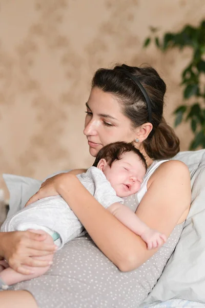 Baby sleeping with mom in her arms. Mom and newborn baby. Mom hugs and holds the newborn baby in her arms, the newborn sleeps in her mother's breast, light gentle tone, the concept of motherhood and a — Stock Photo, Image