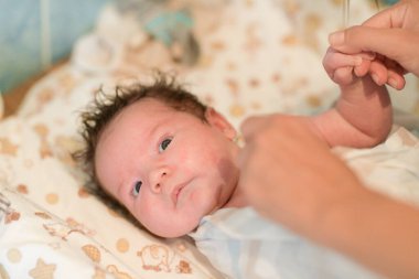 Anne banyo yaptıktan sonra bebeği ovuyor. Çocuk gülümsedi ve banyo yaptıktan sonra mutlu oldu. Anne, duş aldıktan sonra bebeğin saçlarını ve başını havluyla kurular ve ovar. Aile kavramı ve