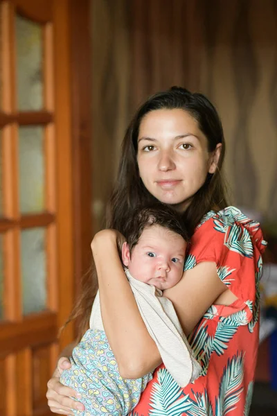 Mother gently hugs the baby. at home. Mom and newborn baby. Mom hugs and holds the newborn baby in her arms, the newborn sleeps in her mother's breast, light gentle tone, the concept of motherhood and — Stock Photo, Image