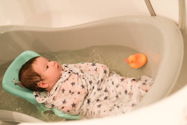 bathing a newborn at home. A picture of a newborn baby from the first bathroom. clipart