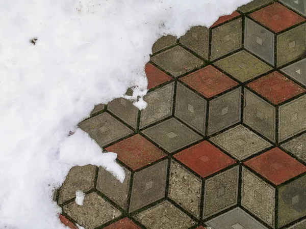 Fayans arkaplanda kar. Gri beton kiremitlerden yapılmış kaldırımda eriyen karın yakın plan fotoğrafı..