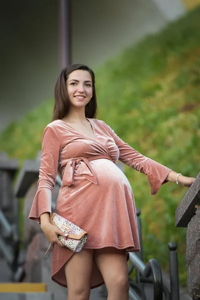 Pregnant girl posing on the stairs. brunette in a velor dress. in the open air — Stockfoto