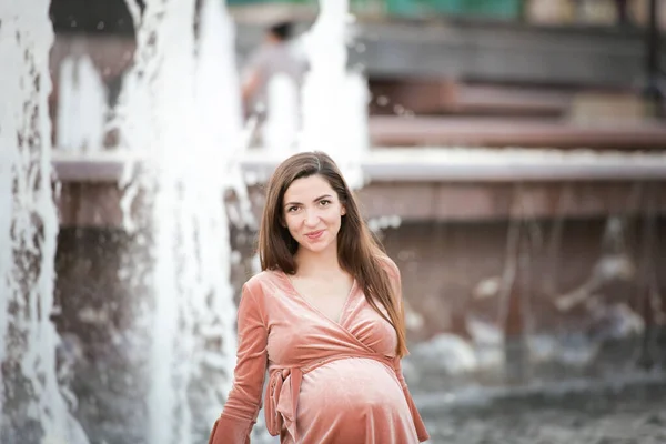 Schwangere Mädchen in der Nähe des Brunnens. glückliche und unbeschwerte Schwangerschaft. — Stockfoto