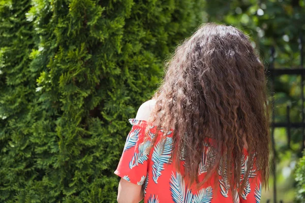 Cheveux bouclés dans la rue, fond. Gros plan portrait d'une jeune belle femme aux longs cheveux bouclés bruns posant sur fond architectural . — Photo