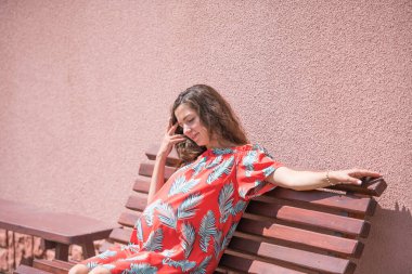 Hamile bir kız bankta oturuyor. Yazı için bir yer. Elbiseli güzel hamile kız..