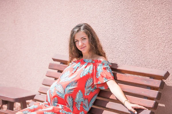 Una chica embarazada está sentada en un banco. lugar para la inscripción. Hermosa chica embarazada en vestido . — Foto de Stock