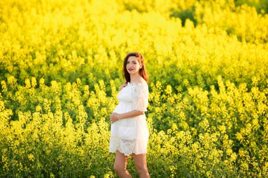 Güzel, hamile, esmer, güzel, hamile bir kadın. Sevgi ve özenle karnına dokunuyor. Kalp şeklinde..