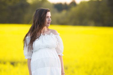 Güzel, hamile, esmer, güzel, hamile bir kadın. Sevgi ve özenle karnına dokunuyor. Kalp şeklinde..