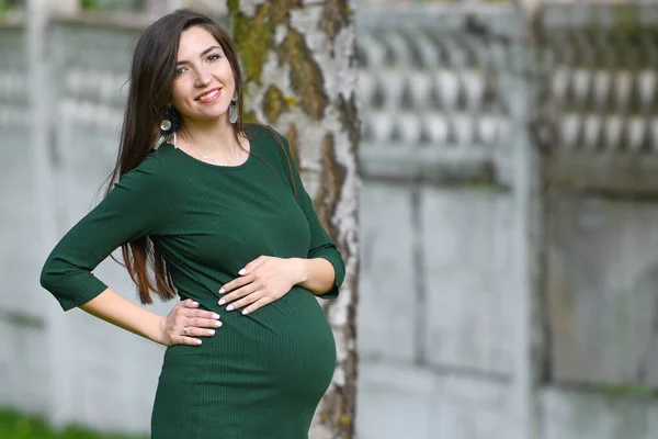 Fille enceinte dans une robe verte. Portrait d'une femme enceinte à l'extérieur, nouveau concept de vie — Photo