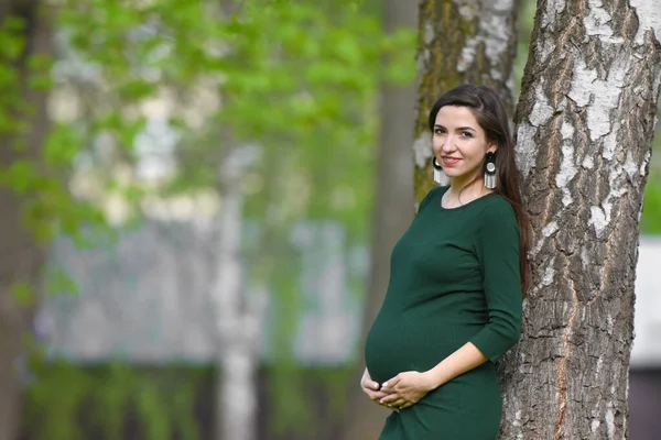 Fille enceinte dans une robe verte. Portrait d'une femme enceinte à l'extérieur, nouveau concept de vie — Photo