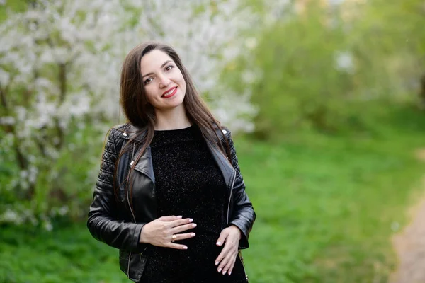 Une fille enceinte dans le jardin. Femme enceinte se sentant heureuse avec une nouvelle vie à la maison de jardin tout en prenant soin de son enfant. La jeune mère enceinte tenant le bébé dans le ventre enceinte. Soins prénatals de maternité — Photo