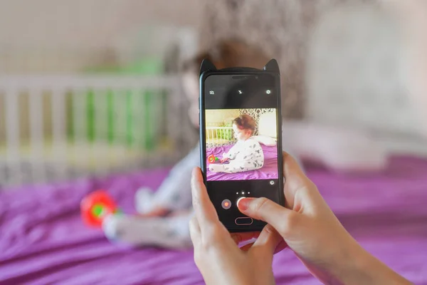 Anne telefonda bebeğinin fotoğrafını çekiyor. Anne, yeni doğmuş bebeğinin fotoğrafını akıllı telefondan çekiyor. Aile anıları.
