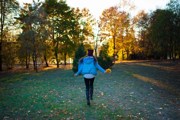 Девушка бежит в осенний парк. Бегущая женщина бегунья солнечный яркий свет на фоне осеннего парка. Девушка радуется осенней листве. Радость осени . — стоковое фото