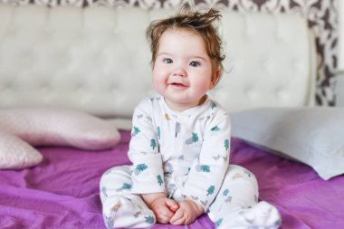 Bebek yatakta kameraya poz veriyor. Çocuk yatakta oynuyor..