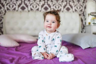 Bebek yatakta kameraya poz veriyor. Çocuk yatakta oynuyor..