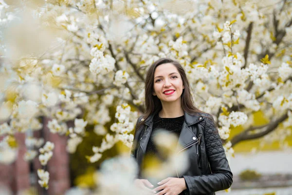 Chica embarazada en el jardín florecido. hermosa chica embarazada en un vestido negro está de pie en un jardín florecido — Foto de Stock