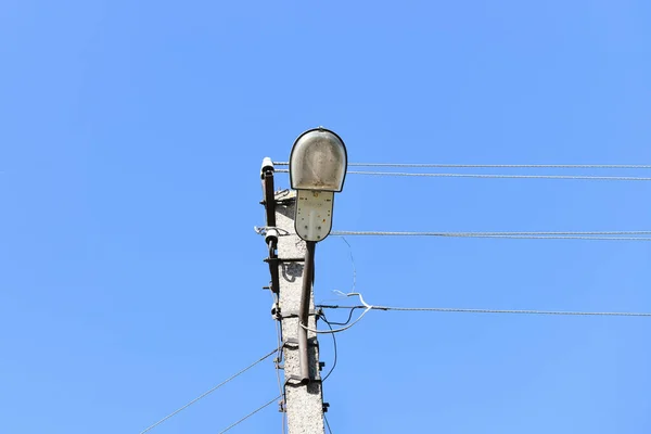 曇った青空を背景にランプポストと有線電気の伝送のための古いコンクリート電柱。私を許しなさい。電気の供給方法 — ストック写真