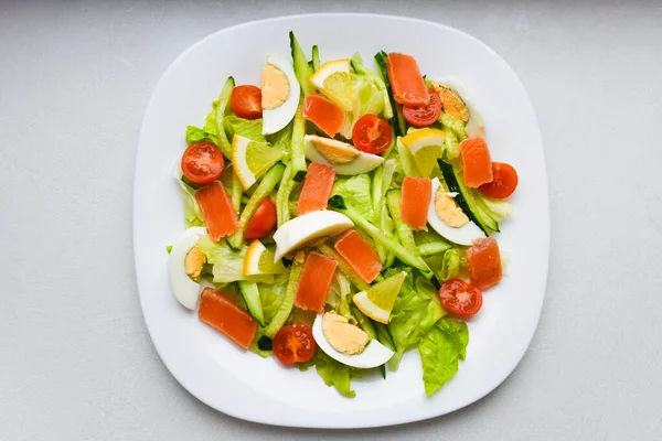 Овощной салат на белой тарелке. Свежий салат с яйцом, помидорами, шпинатом и авокадо на белом деревянном фоне вид сверху. Здоровое питание . — стоковое фото