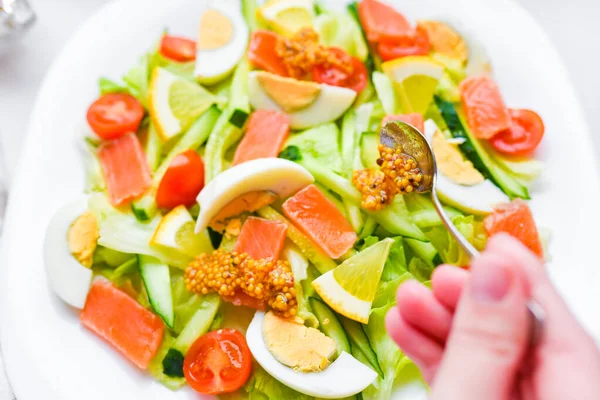 Aggiunga la senape a insalata vegetale. insalata di verdure con mani umane. su un piatto bianco. aggiungere spezie . — Foto Stock