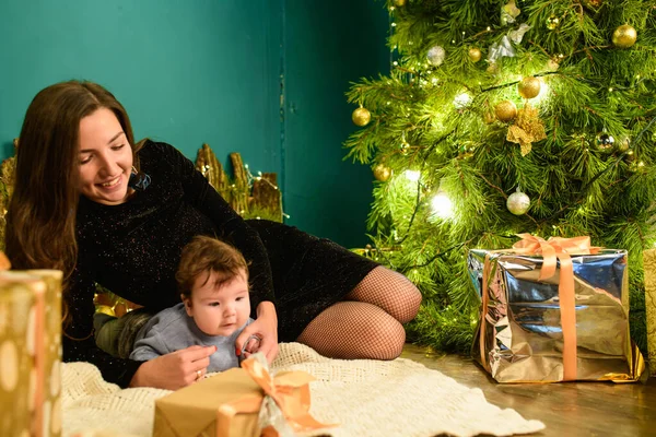 Weihnachten und Muttertag. Weihnachten und Menschen Konzept - Mutter und Baby mit Geschenken. vor weihnachtlichem Hintergrund. Warme Weihnachten. — Stockfoto