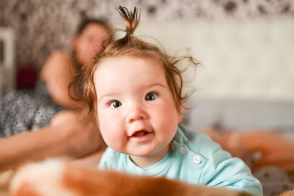 Een klein kind met een paardenstaart op zijn hoofd. Grappig kind. naast mama veel plezier — Stockfoto