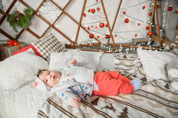 A child from 0 to 1 years old is in bed in a Christmas setting. Happy New Year and Merry Christmas