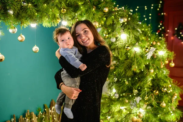 happy mom with baby in new year setting. a young woman and a seven-year-old child look at the camera in a Christmas setting. family at Christmas. Happy Mom and son at the Christmas tree