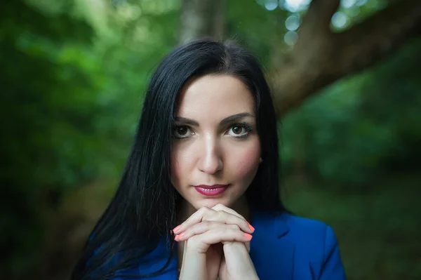 Una chica reza por la naturaleza. Al aire libre. morena con ojos expresivos tomados de la mano en su lugar mirando a la cámara. En un traje azul en el contexto de la naturaleza . — Foto de Stock