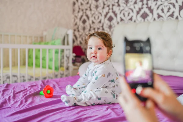 Mama fotografiert ihr Baby am Telefon. Die Mutter macht ein Foto von ihrem Neugeborenen auf dem Smartphone. Familienerinnerungen. — Stockfoto