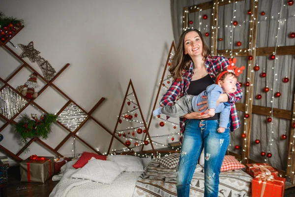 Noel 'de anneyle bebek. Mutlu aile annesi ve küçük oğlu Noel tatillerinde evde oynuyorlar. Yeni yıl tatili. Annenle birlikte Noel ağacıyla süslenmiş bir odada bebek. Po — Stok fotoğraf